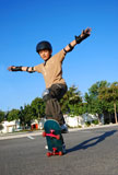 Boy+doing+stunts+on+a+skateboard+in+afternoon+sun+with+blue+sky+in+the+background+