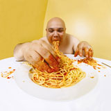 An+overweight+man+enjoying+a+plate+of+spaghetti.+Shot+with+fish-eye+lens.+Focus+is+on+the+face.+
