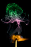 Magic+matchstick+with+colorful+smoke+over+black+background+