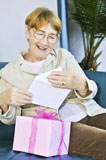 Elderly+woman+opening+birthday+card+and+present+
