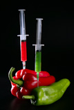 Injection+with+syringe+to+red+and+green+peppers+over+black+background