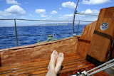 man+feet+relax+on+golden+wooden+old+sailboat+blue+sea+summer+vacation+dream