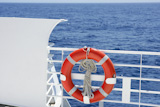Cruise+white+boat+handrail+detail+in+blue+sea+and+round+orange+buoy