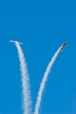 A+pair+of+aerobatic+airplanes+trailing+smoke+flies+separate+in+smooth+arcs+against+a+bright+blue+sky