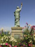 Miniature+Statue+Of+Liberty+Replica+Surrounded+By+Tropical+Flowers+And+Looking+Out+To+Sea