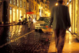 Walking+Along+A+Narrow+Cobblestone+Street+In+The+Rain