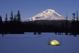 Lone+Tent+Lit+Up+in+Darkness+With+Snow-Capped+Mountain+in+Background