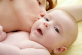mother+kissing+little+baby+smiling+on+white+background