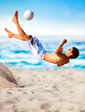 Young+man+playing+soccer+on+beach.