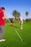 golf+woman+player+putting+golf+ball+and+man+holds+flag
