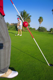golf+woman+player+putting+golf+ball+and+man+holds+flag