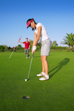 golf+woman+player+green+putting+hole+golf+ball+a+man+holding+flag