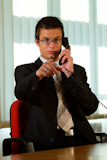 A+young+male+executive+on+the+phone+and+pointing+into+the+camera