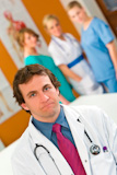 A+male+consultant+with+other+medical+staff+out+of+focus+in+the+background