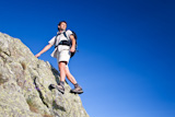 Young+man+standing+on+a+rock+over+a+deep+blue+sky+background.+Large+copy-space+on+the+right.+Low+angle+view