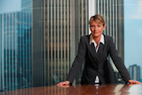 Business+woman+leaning+on+chair+in+boardroom+looking+at+camera