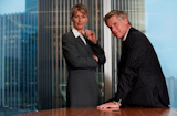 Senior+business+man+and+woman+in+a+boardroom+smiling+looking+at+camera