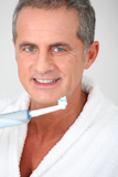 Portrait+of+mature+man+using+electric+toothbrush