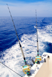 boat+fishing+trolling+in+deep+blue+sea+with+rods+and+reels