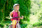 Children+girl+riding+bicycle+outdoor+in+forest+smiling+with+helmet