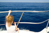 Blond+little+girl+rear+view+sailing+in+boat+in+blue+Ibiza+sea
