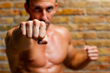 muscle+boxer+shaped+man+fist+to+camera+on+brickwall