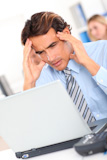 Businessman having a headache in front of laptop