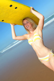 Beautiful blond woman standing with surfboard