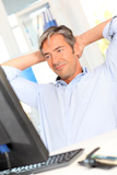 Man relaxing in office with stretched arms