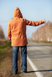 man with orange coat on the empty road, selective focus