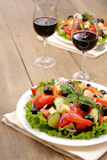 Vegetable salad and glass of red wine on the oak table