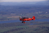 Red+Bi-wing+Plane+Flying+Over+Countryside