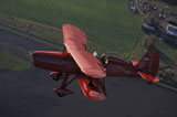 Red+Bi-wing+Plane+Flying+Over+Water+And+Farms
