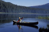 Man+Reeling+In+Fish+From+Canoe+In+Mountain+Lake
