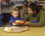 Teacher+Serving+Child+Lunch+In+Preschool+Classroom