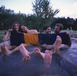 Two+Couples+Sitting+In+An+Outdoor+Hot+Tub+And+Holding+Up+Their+Swimming+Trunks