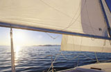 View+of+the+sun+setting+through+the+sails+of+a+sailboat