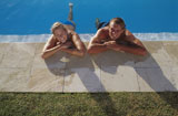 High+angle+view+of+a+young+couple+relaxing+at+poolside
