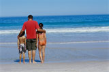 Rear+view+of+a+father+standing+with+his+son+and+daughter+on+the+beach