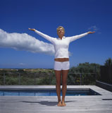 Young+woman+standing+near+a+pool+with+her+arms+outstretched