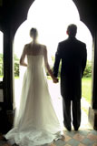 Rear+view+of+a+young+bride+and+groom+holding+hands+in+a+doorway