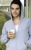 Close-up+of+a+young+man+wearing+a+hooded+shirt+and+holding+a+cup+of+tea