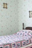 Bedroom+with+patterned+wallpaper+and+a+quilt+on+the+bed