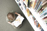 Little+boy+reading+book+beside+library+shelf