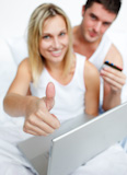 Couple in bed buying on-line successfully