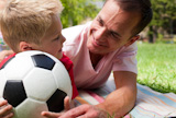 Close-up of an attentive father and his son holding a soccer ball