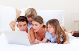 Merry family buying online lying down on bed
