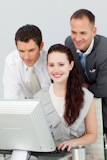 Smiling businesswoman and two businessmen using a PC