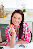 Radiant woman holding an apple sitting in the kitchen