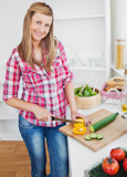 Joyful woman cutting  and cucumber at home